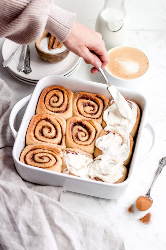 spreading cinnamon rolls with frosting