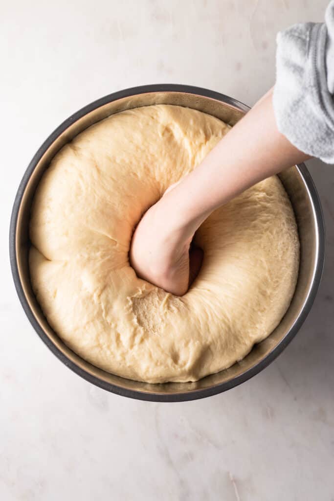 hand punching down cinnamon roll dough to expel gases