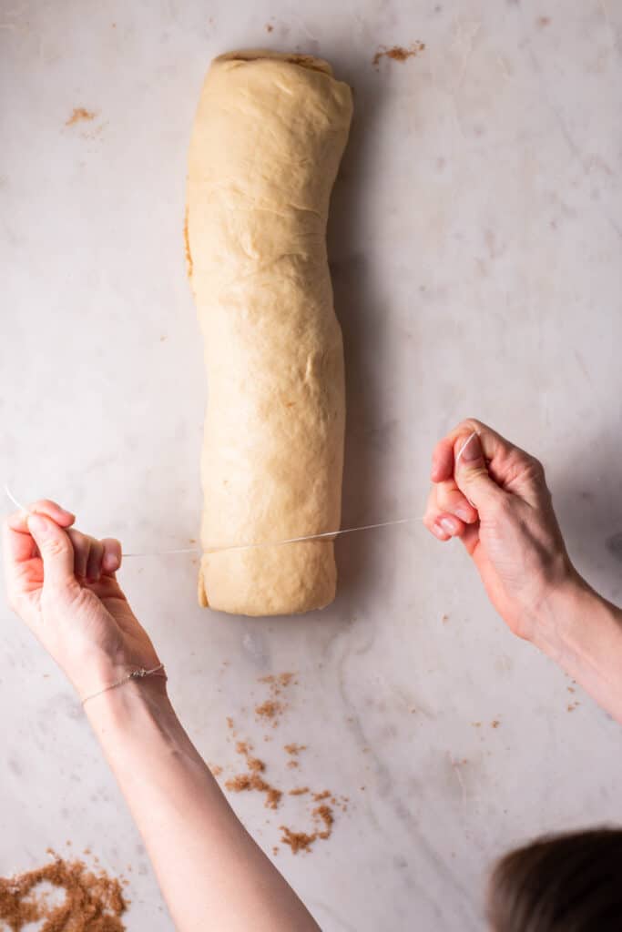 hands cutting cinnamon rolls