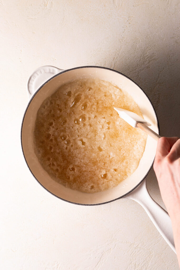 hand stirring sugar and water in a saucepan