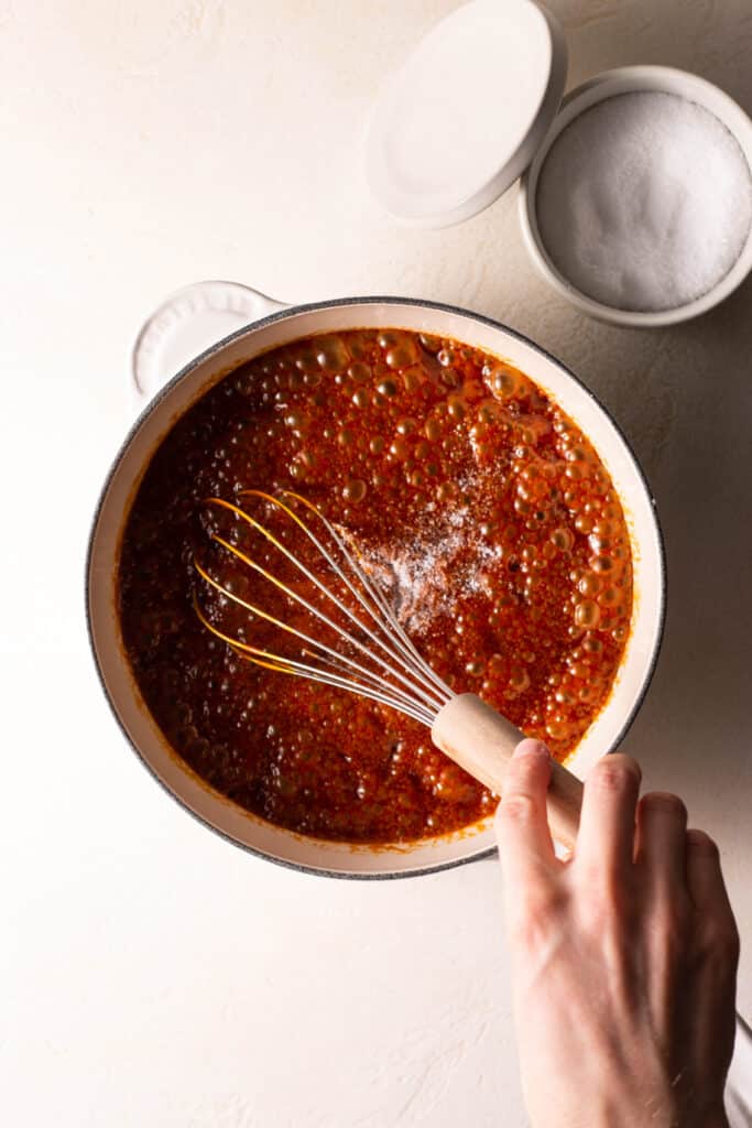 stirring salt into homemade caramel sauce in a saucepan