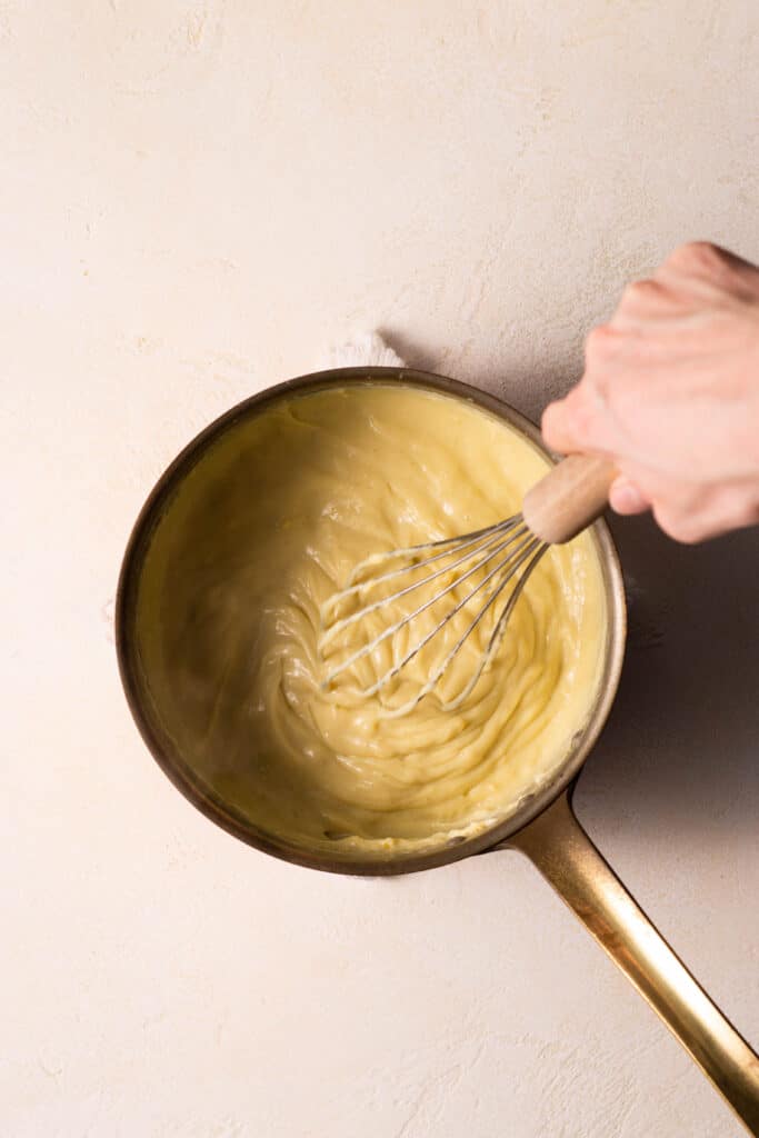 hand whisking pastry cream in a saucepan