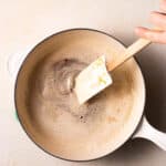 hand stirring brown butter in a saucepan