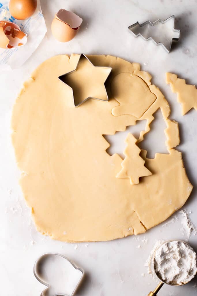 sugar cookie dough rolled out on a floured surface with cut-outs.