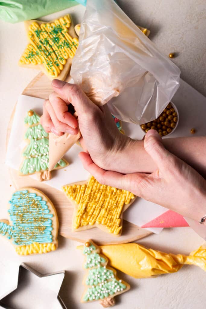 hand frosting sugar cookies on a plate