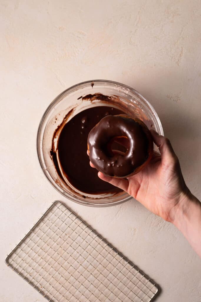 chocolate glazed donut being dipped.