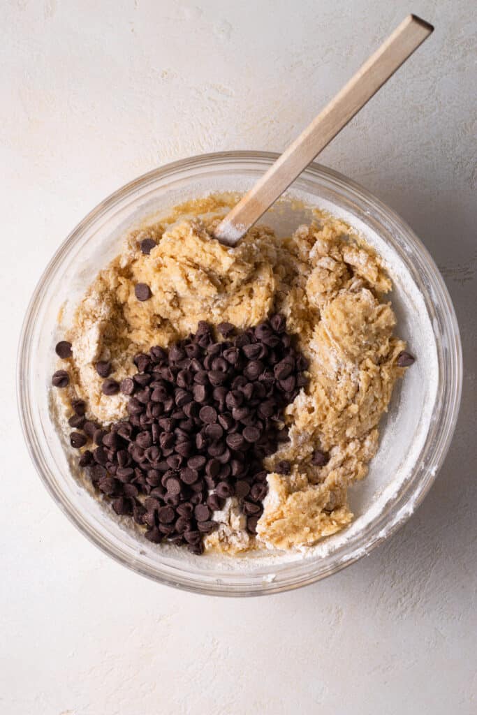 overhead shot of chocolate chips being added to mini skillet cookie dough.