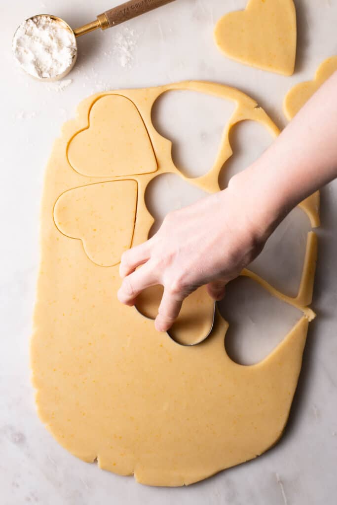 hand cutting out cookies on a surface