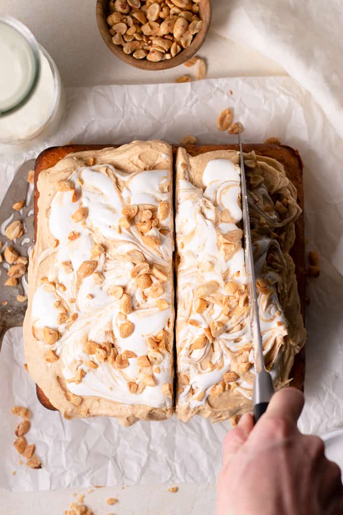 peanut butter banana cake on a board with someone cutting a slice out