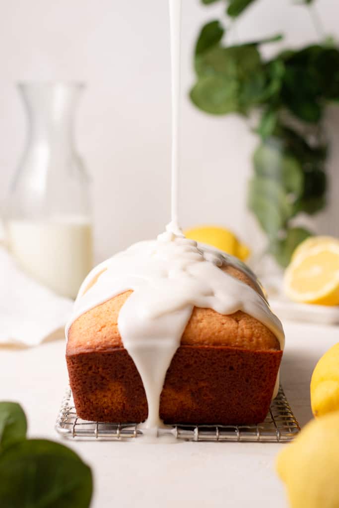 lemon loaf with glaze being poured over top
