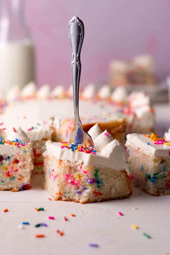 funfetti sheet cake with a bite being taken out of it
