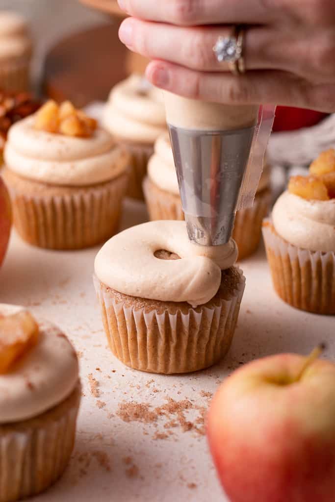 hand piping salted caramel buttercream onto apple pie cupcakes