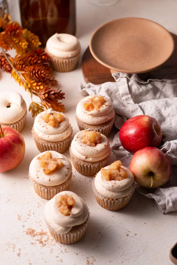 apple pie cupcakes on a board scattered around other fall decorations