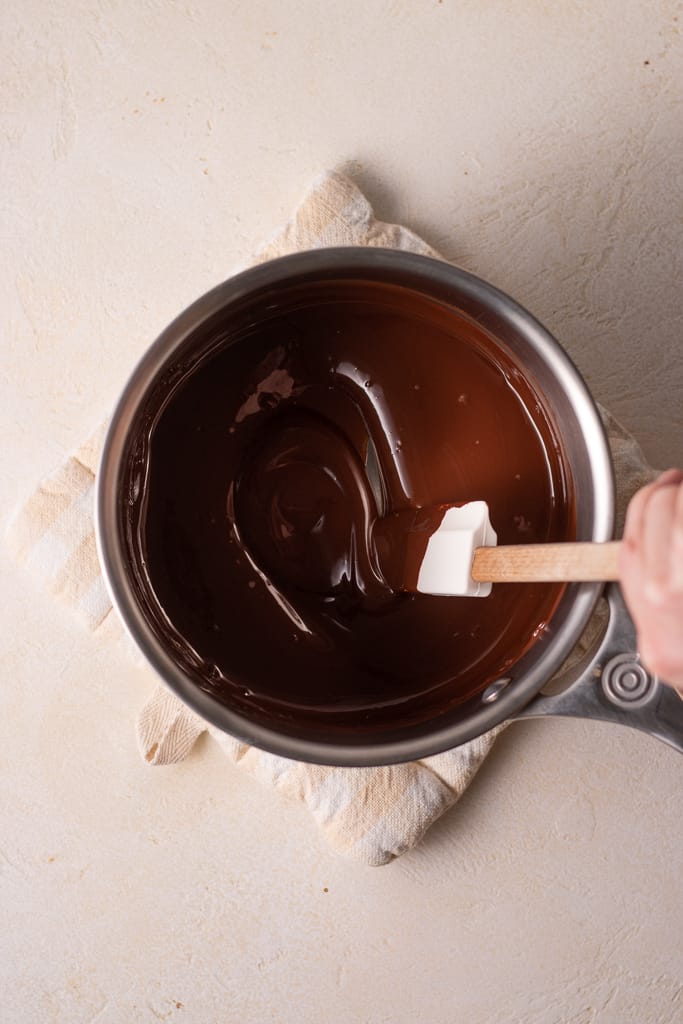 hand stirring melted chocolate in a saucepan