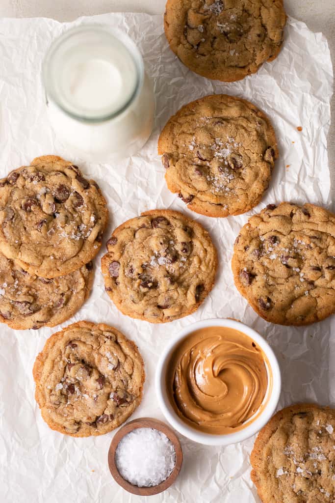 peanut butter chocolate chip cookies on a board surrounded by other cookies and a bowl of peanut butter