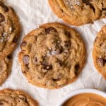 peanut butter chocolate chip cookies on a board surrounded by other cookies and a bowl of peanut butter