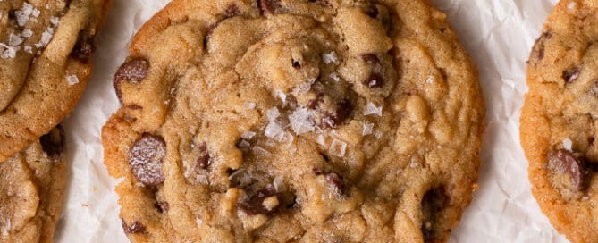 peanut butter chocolate chip cookies on a board surrounded by other cookies and a bowl of peanut butter