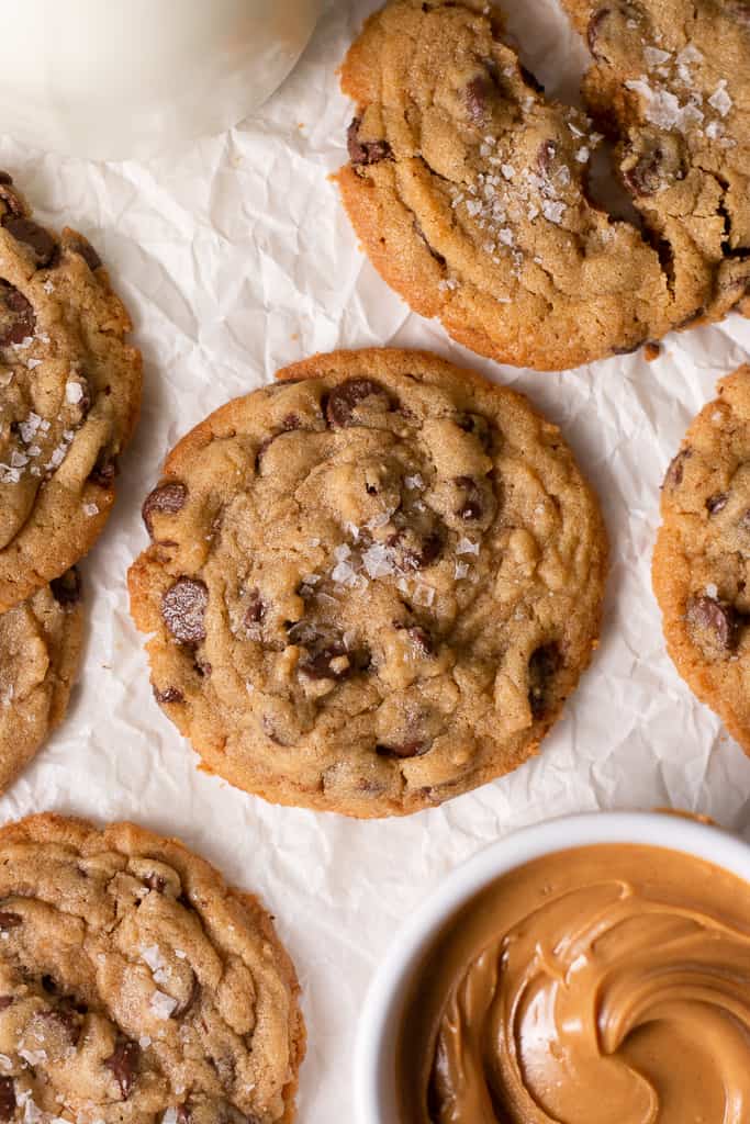 peanut butter chocolate chip cookies on a board surrounded by other cookies and a bowl of peanut butter