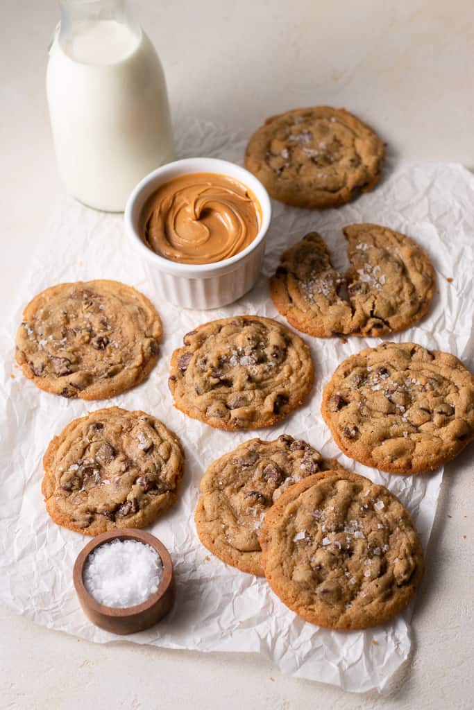 peanut butter chocolate chip cookies arranged on a board with milk and peanut butter