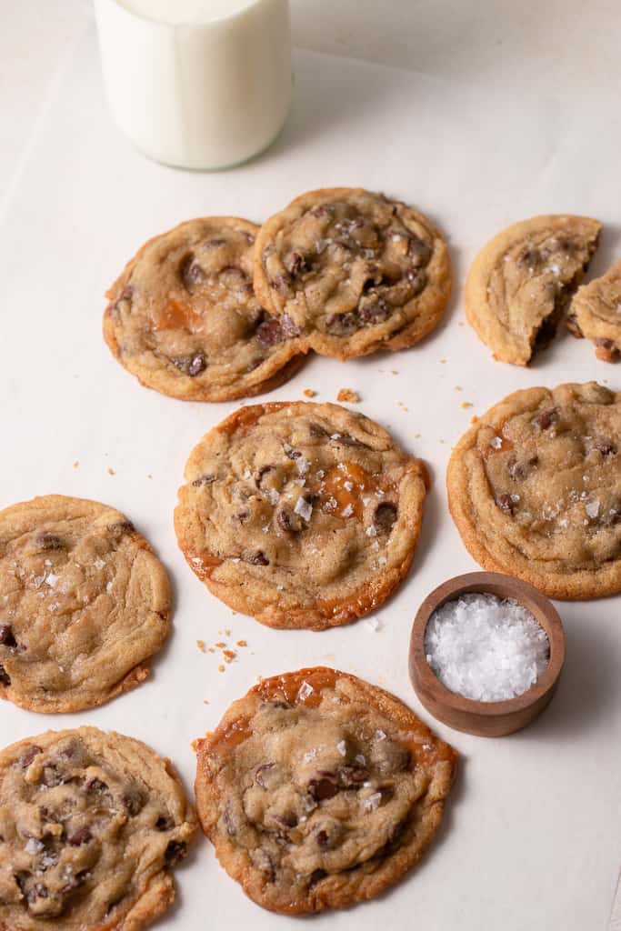 salted caramel chocolate chip cookies on a board with a glass of milk behind them