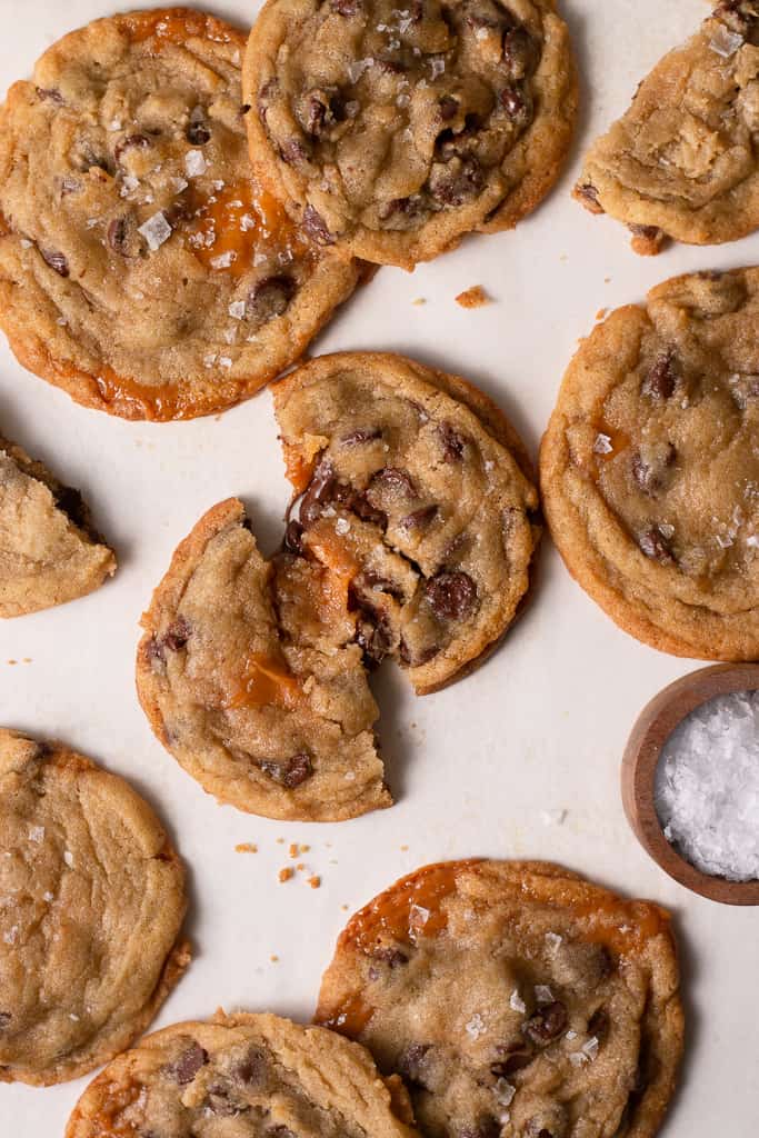 one salted caramel chocolate chip cookie split in half and surrounded by other cookies. 
