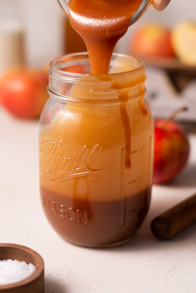 side shot of caramel being poured into a mason jar