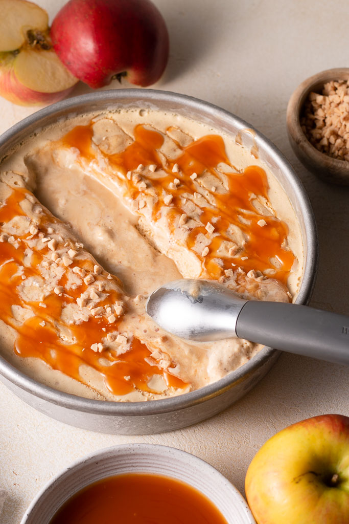 side shot of an ice cream scoop dipping into the caramel apple ice cream.