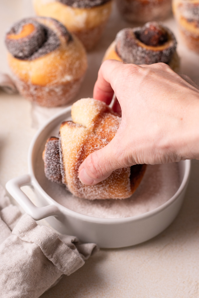 hand coating chocolate filled bun in granulated sugar.