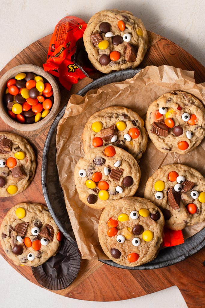 overhead shot of peanut butter monster cookies on a plate surrounded by other candies.