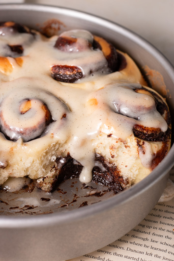 side angle shot of glaze dripping down the side of a cinnamon roll.