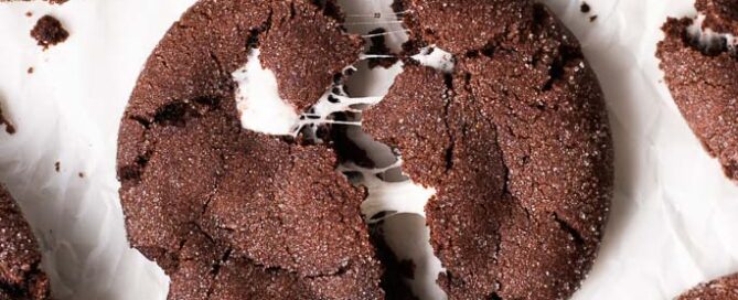 chocolate marshmallow cookie on a board and being pulled apart.