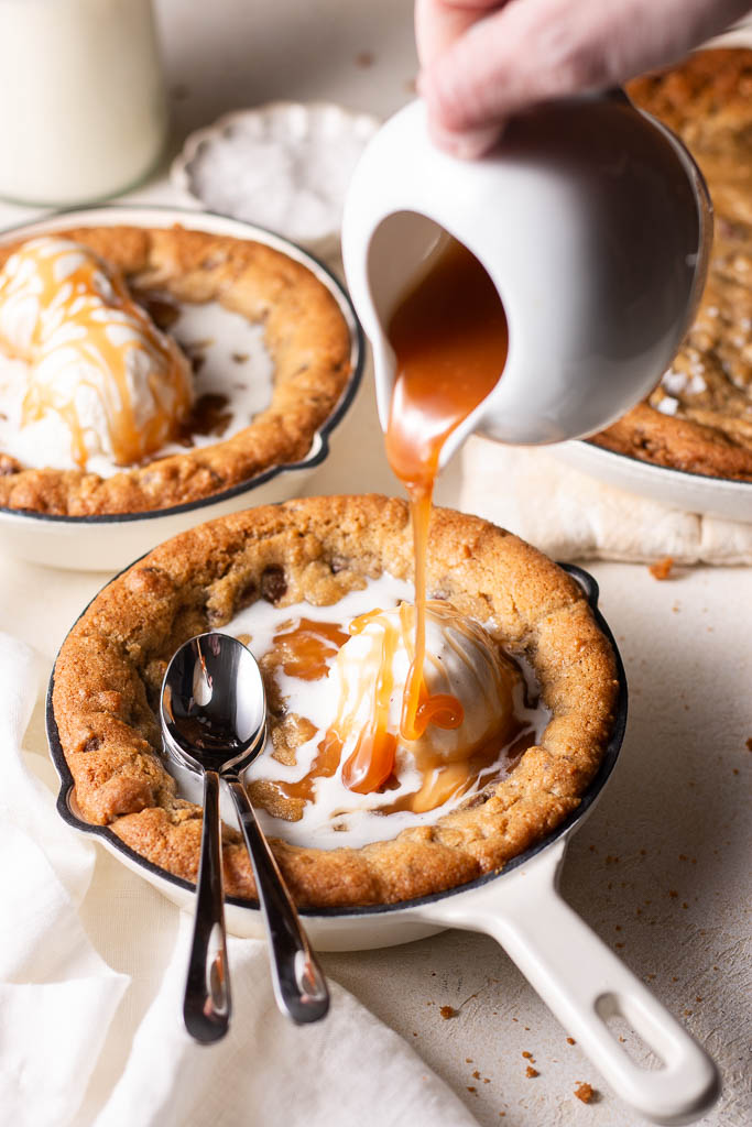 homemade caramel being poured over mini skillet cookies.