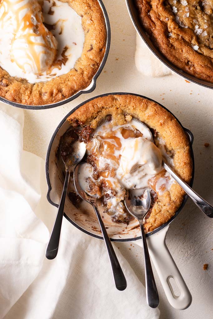 overhead shot of mini skillet cookies with ice cream and caramel sauce.