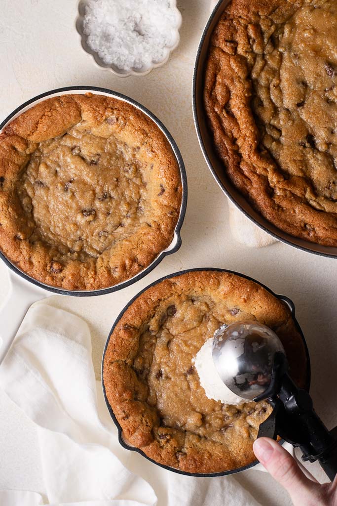 overhead shot of a hand adding ice cream to mini skillet cookies.