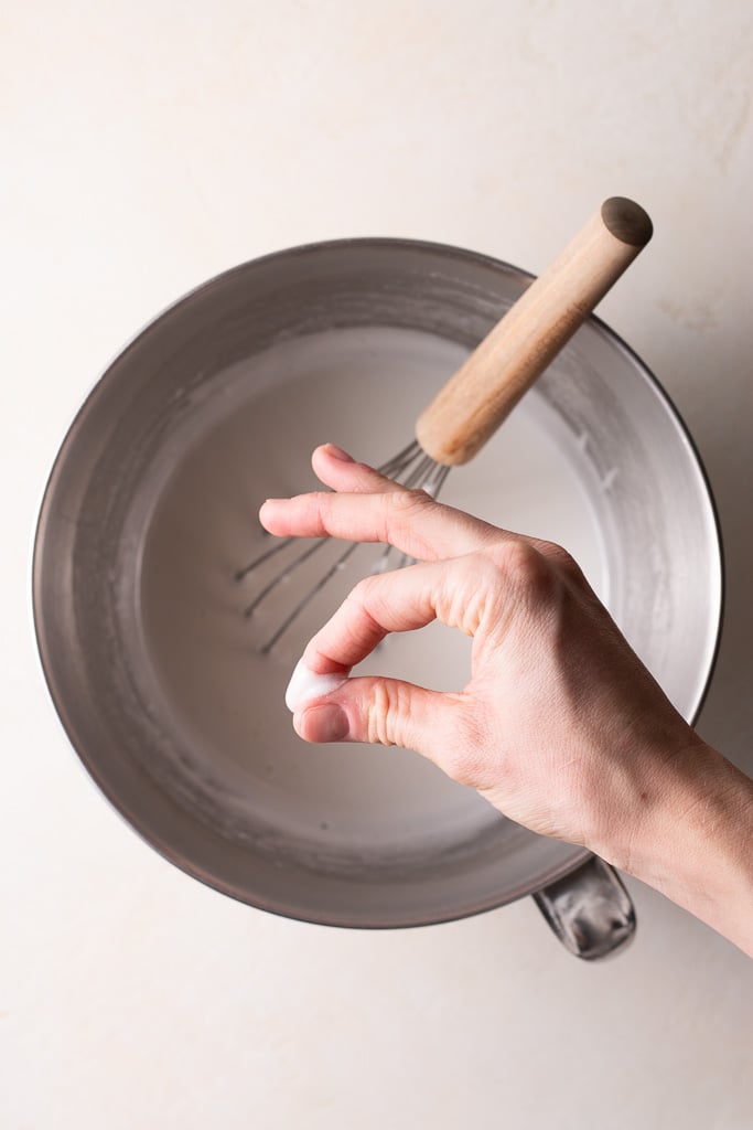 testing the sugar and egg whites between fingers to see if it's properly dissolved.